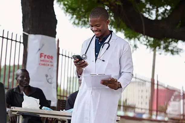 Un médecin sourit en lisant un message sur son téléphone
